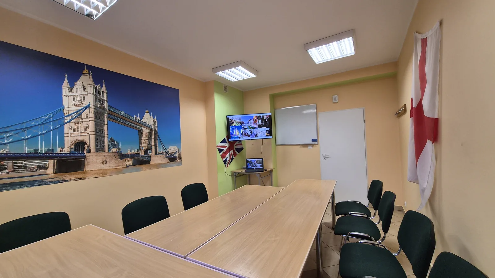 Sala szkoleniowa English Colours w Białymstoku — stoły, krzesła, telewizor, tablica suchościeralna i fototapeta z Tower Bridge